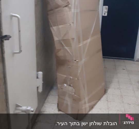 קופסה גדולה מקרטון עם נזקי הובלה במסדרון